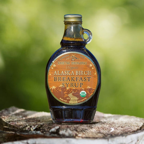 Kahiltna Birchworks Alaska Breakfast Syrup, 8 fl oz glass bottle made with Alaska Pure Birch Syrup, resting on a birch log