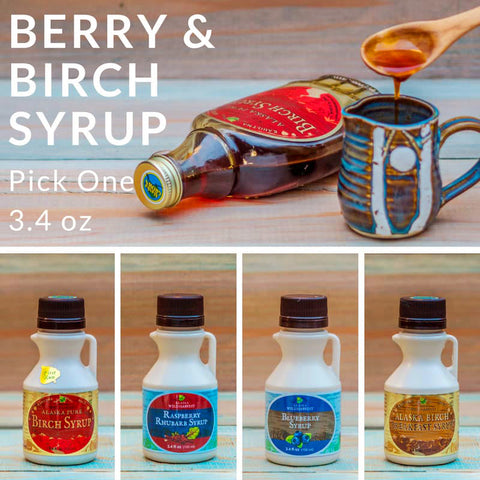 Alaska native berry and birch syrups with a bottle and mug on a wooden surface.