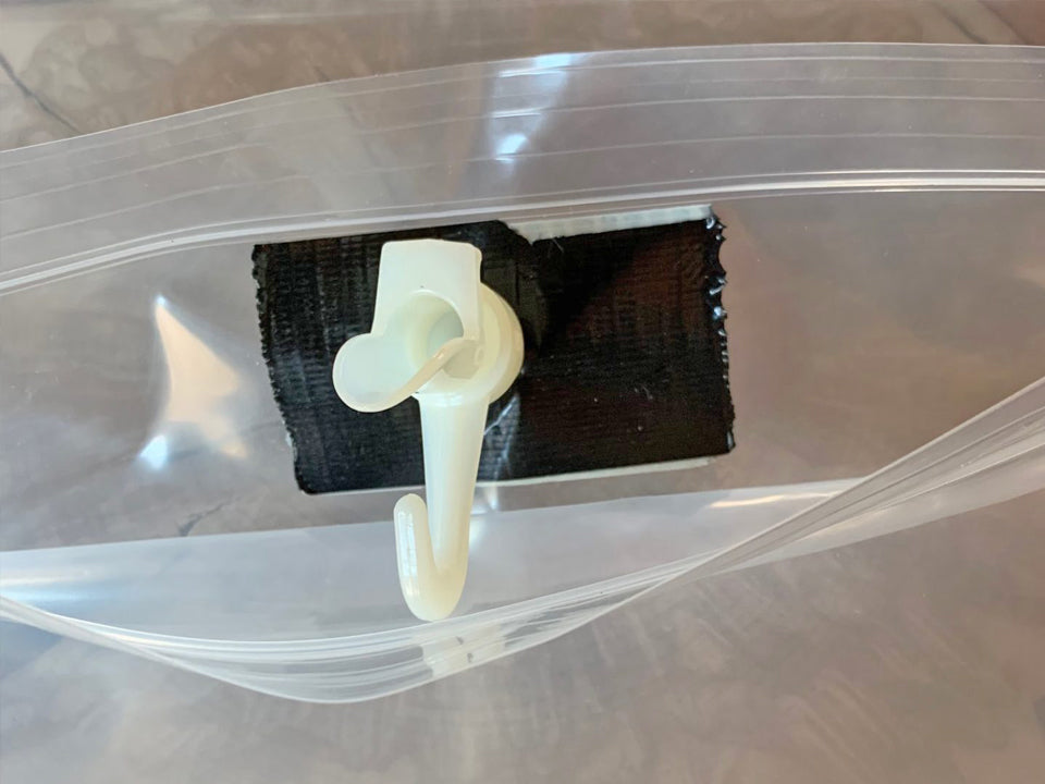 White plastic hook attached to a clear plastic sap bag with a brown background