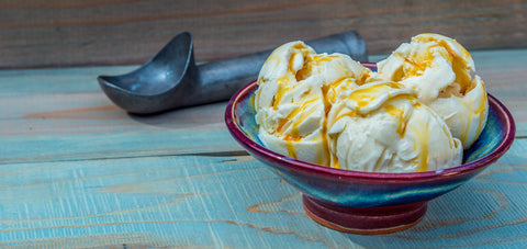 Bowl of ice cream with birch syrup drizzle on a wooden surface