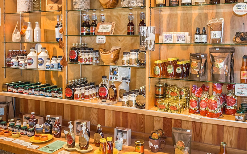 Shelf displaying various birch syrup bottles and products in a store setting