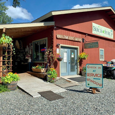 Red building with Kahiltna Birchworks sign and outdoor seating area.
