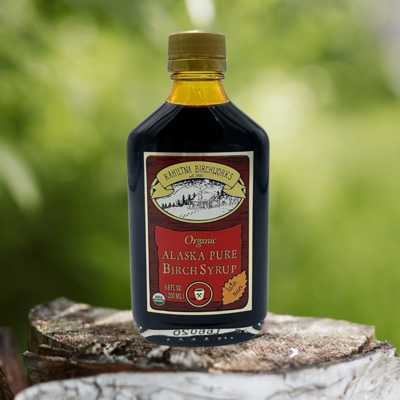 Kahiltna Birchworks Organic Alaska Pure Birch Syrup, 6.8 fl oz late run bottle resting on a birch log